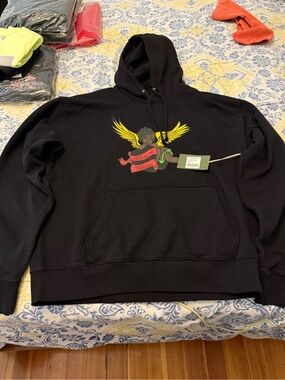Denim Tears Cherub Men’s Black Graphic Hoodie with Yellow Wing Motif